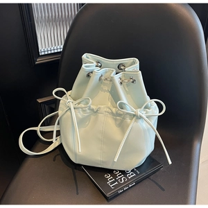 Detail of light blue bucket backpack with drawstring chain and leather bow accents