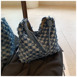 Detail of checkered denim tote bag with frayed edges and textured fabric surface