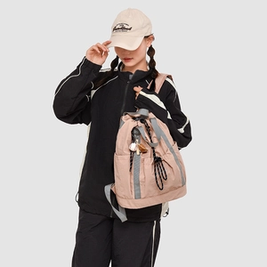 Zaino in nylon rosa con coulisse, cinghie grigie e tasca laterale indossato da modella