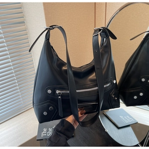 Detail of black motorcycle hobo bag featuring silver rivets and industrial metal zippers