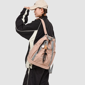 Dettagli dello zaino in nylon rosa con coulisse, spalline grigie e ciondolo da baseball
