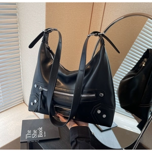 Detail of black crescent hobo bag with silver studs, zippers and adjustable shoulder straps