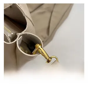 Détail du crochet en métal doré et des coutures en cuir sur un sac seau de couleur beige
