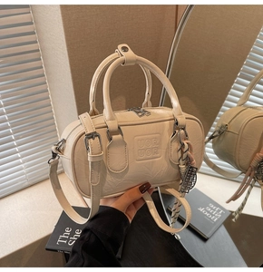 Détail d'un sac Boston crème avec texture en cuir froissé et logo embossé élégant
