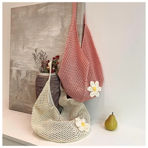 Detail of hand-woven hollow knit tote bags with white floral accents in pink and beige