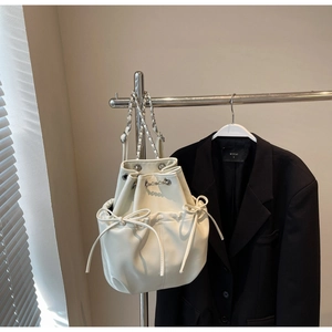 Detail of white PU leather bucket backpack featuring bow pockets and silver chain straps