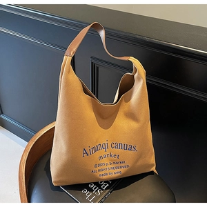 Détail du sac hobo en toile marron avec bandoulière en cuir et design bleu