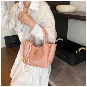 Sac seau rose avec ferrures dorées et breloque décorative porté par un mannequin