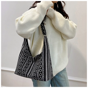 Detalle de un bolso tote de punto geométrico en blanco y negro con ropa casual