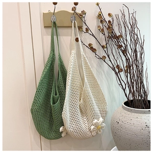 Detail of woven crochet tote bags in green and cream with floral texture and hollow knit