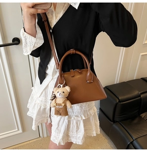 Close-up of a brown retro bowling bag with a cute bear plush pendant in a home setting