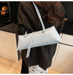 Detail of light blue patent leather baguette bag with dual thin shoulder straps