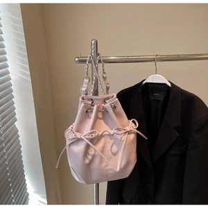 Detail of pink bucket bag featuring drawstring closure and side leather bow accents