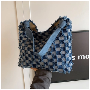 Detail of blue and white checkered denim tote bag with frayed fringe texture and large capacity