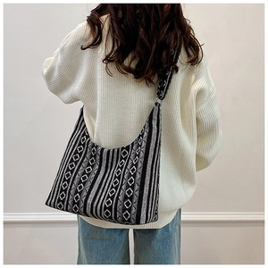 Vista trasera de una modelo con bolso hobo tejido con patrones geométricos étnicos en negro