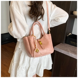 Vue détaillée du sac seau rose en cuir avec fermoir doré et accessoire clochette