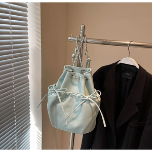 Detail of light mint green bucket bag with bow accents and drawstring chain strap