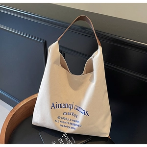 Détail du sac cabas en toile beige avec anses en cuir marron et imprimé graphique bleu