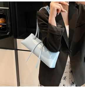 Light blue patent leather baguette bag shown as a shoulder bag on a model's arm