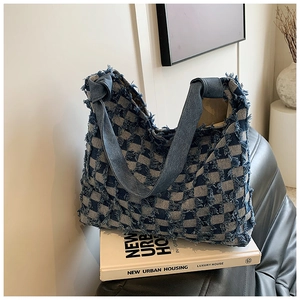 Detail of blue and white checkered denim tote bag with frayed edges and knotted strap