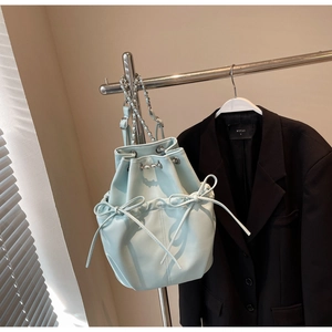 Detail of light blue bucket backpack featuring drawstring closure and ribbon side accents