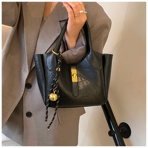 Détail d'un sac seau noir avec fermoir tournant doré et pendentif boule décoratif