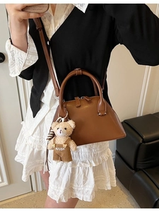 Brown matte leather saddle bowling bag with teddy bear pendant shown in a mirror selfie