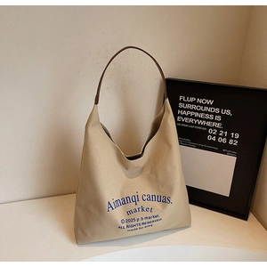 Gros plan du sac cabas en toile beige avec anses brunes et lettrage bleu moderne