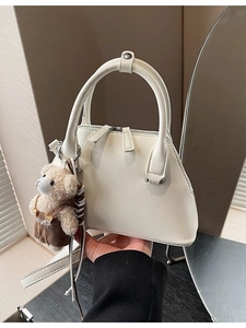 Elegant off-white leather bowling handbag with a cute brown plush bear charm detail