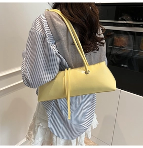 Detail of yellow baguette bag featuring a stylish long tassel zipper on the shoulder strap