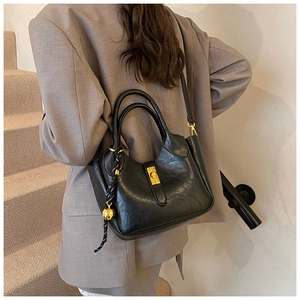 Détail du sac seau noir en cuir ciré avec fermoir doré et pendentif boule dorée