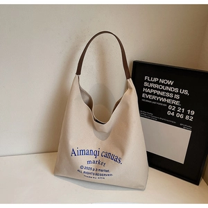Détail du sac cabas en toile beige avec anses en cuir marron et texte bleu vintage