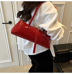Detailed view of the dark red glossy patent leather baguette bag styled on a shoulder