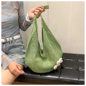 Detail of green crochet tote bag featuring white floral applique and openwork mesh design