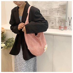 Pink hand-woven crochet tote bag with white daisy detail for summer beach travel