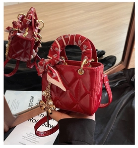 Close-up of red quilted patent leather mini bag with silk scarf handle and pearl charm