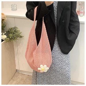 Detail of pink crochet hobo bag with knit mesh texture and a white 3D flower decoration