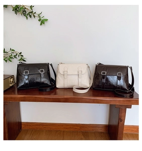 Sacs à bandoulière rétro en noir, beige et marron disposés sur un banc en bois vintage