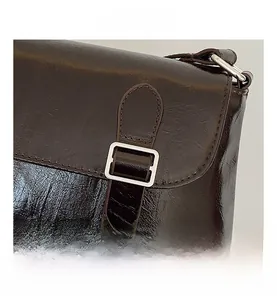 Gros plan sur la texture en similicuir marron foncé et le fermoir métallique de ce sac