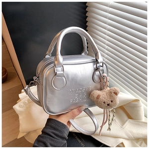 Close-up of metallic silver pillow bag featuring embossed logo and brown teddy charm