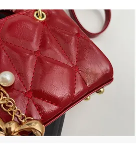 Detailed view of red quilted leather bag with pearl ornament and gold bow charm