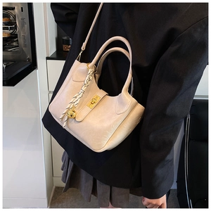 Détail du sac seau beige avec fermoir rotatif doré et accessoire de corde tressée