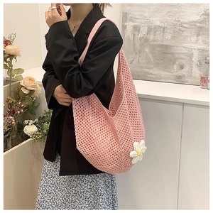 Detail of pink woven tote bag with a white daisy flower charm worn over the shoulder