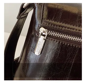Gros plan du zip argenté et de la gravure C&HEKA sur le sac en cuir marron foncé