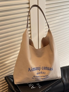 Grand sac cabas en toile beige avec anses en cuir marron et texte bleu en décor intérieur