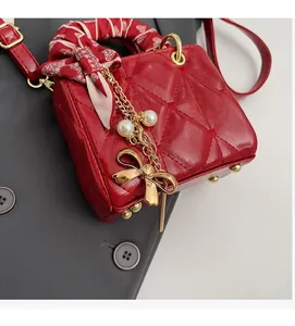 Macro shot of red quilted mini handbag with silk-wrapped handle and pearl bow charm detail