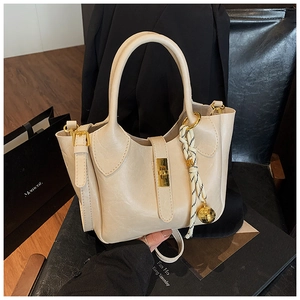 Détail du sac seau crème avec fermoir doré et breloque tressée en cadre chic