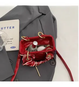Internal view of red glossy patent handbag with silk scarf and daily essentials
