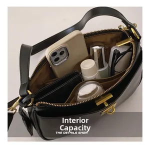 Detail view of the black leather crossbody bag interior with gold zippers and compartments
