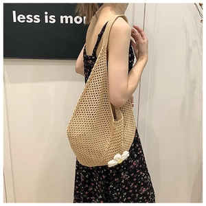 Close-up of woven straw tote bag with daisy ornament shown from a side view